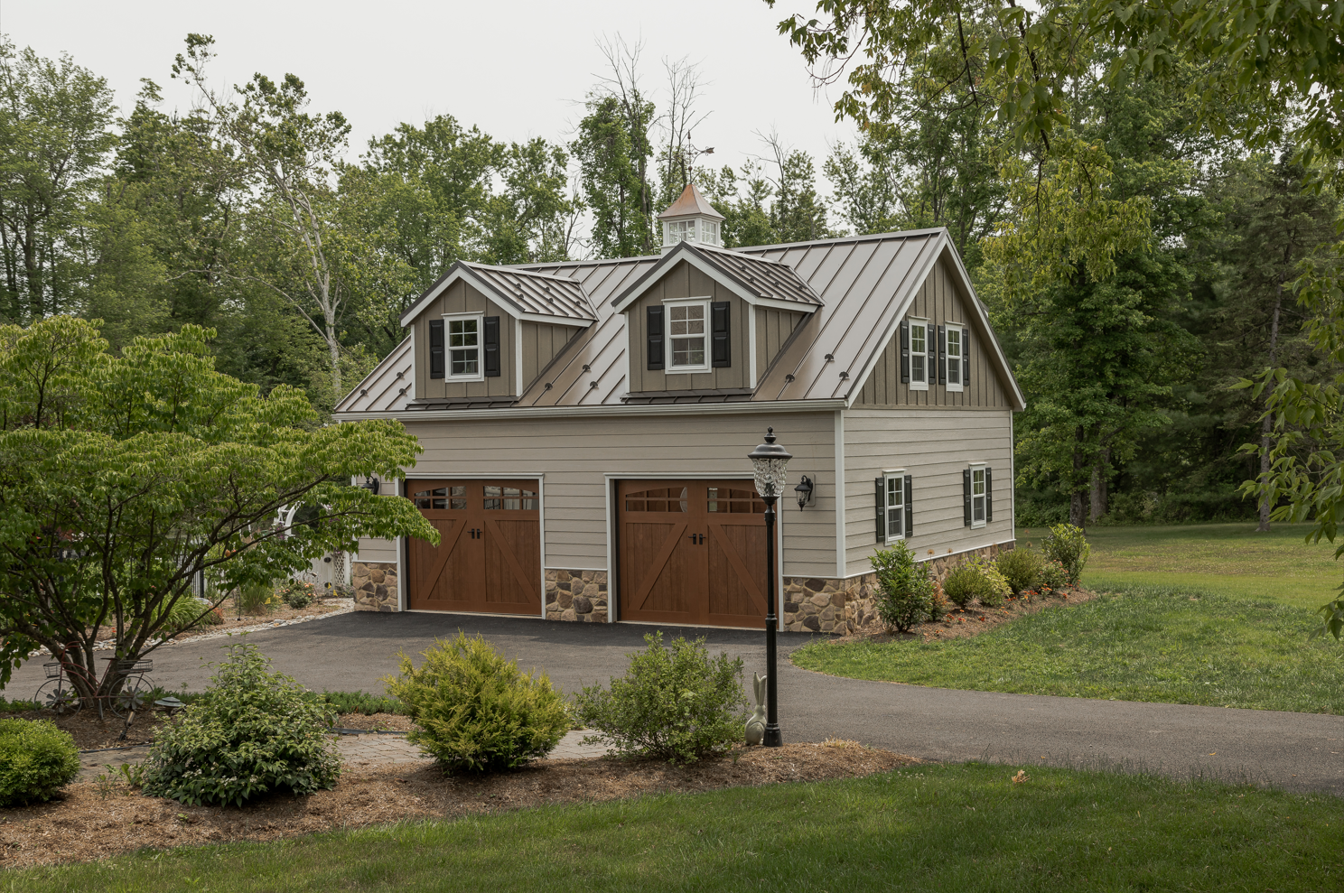 White two-story garage with dark garage doors and dormer windows at sunset