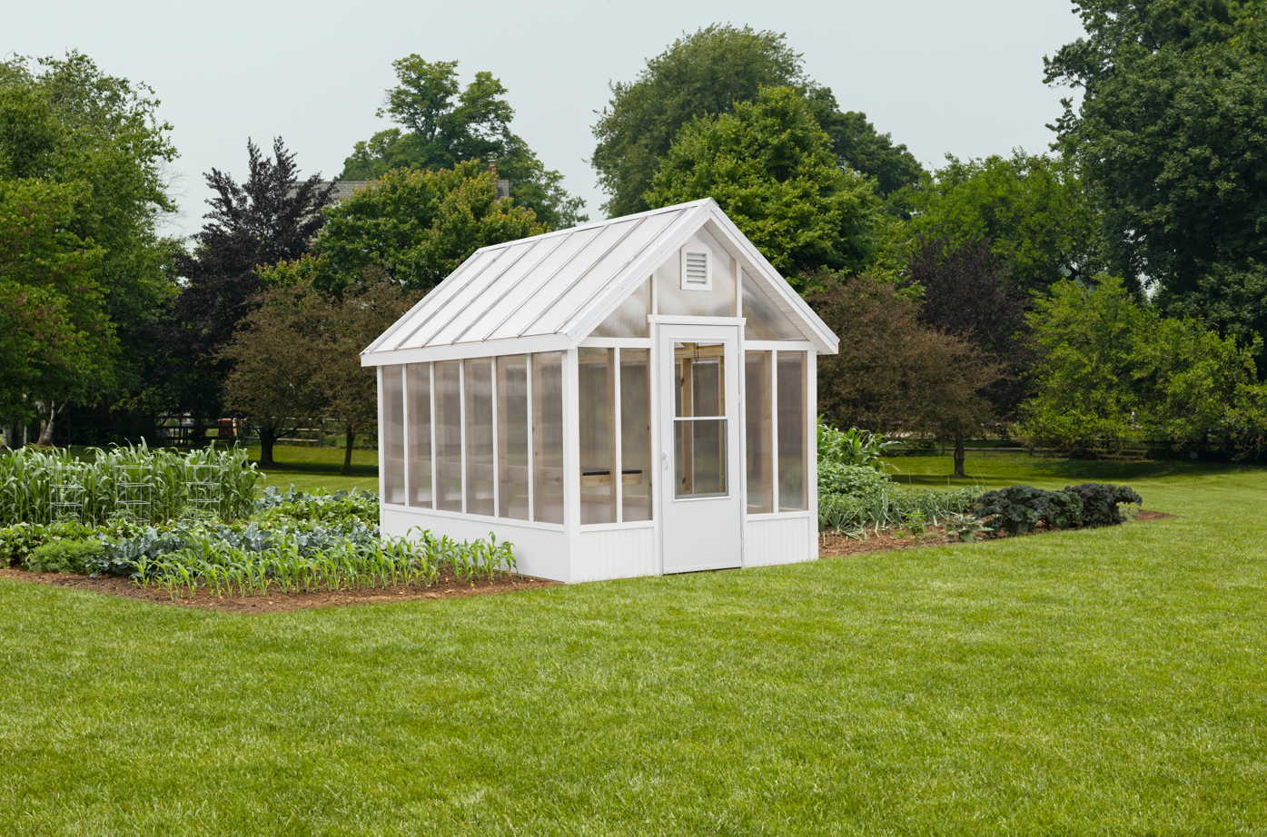 Cream chalet-style greenhouse with clear polycarbonate roof and wood door