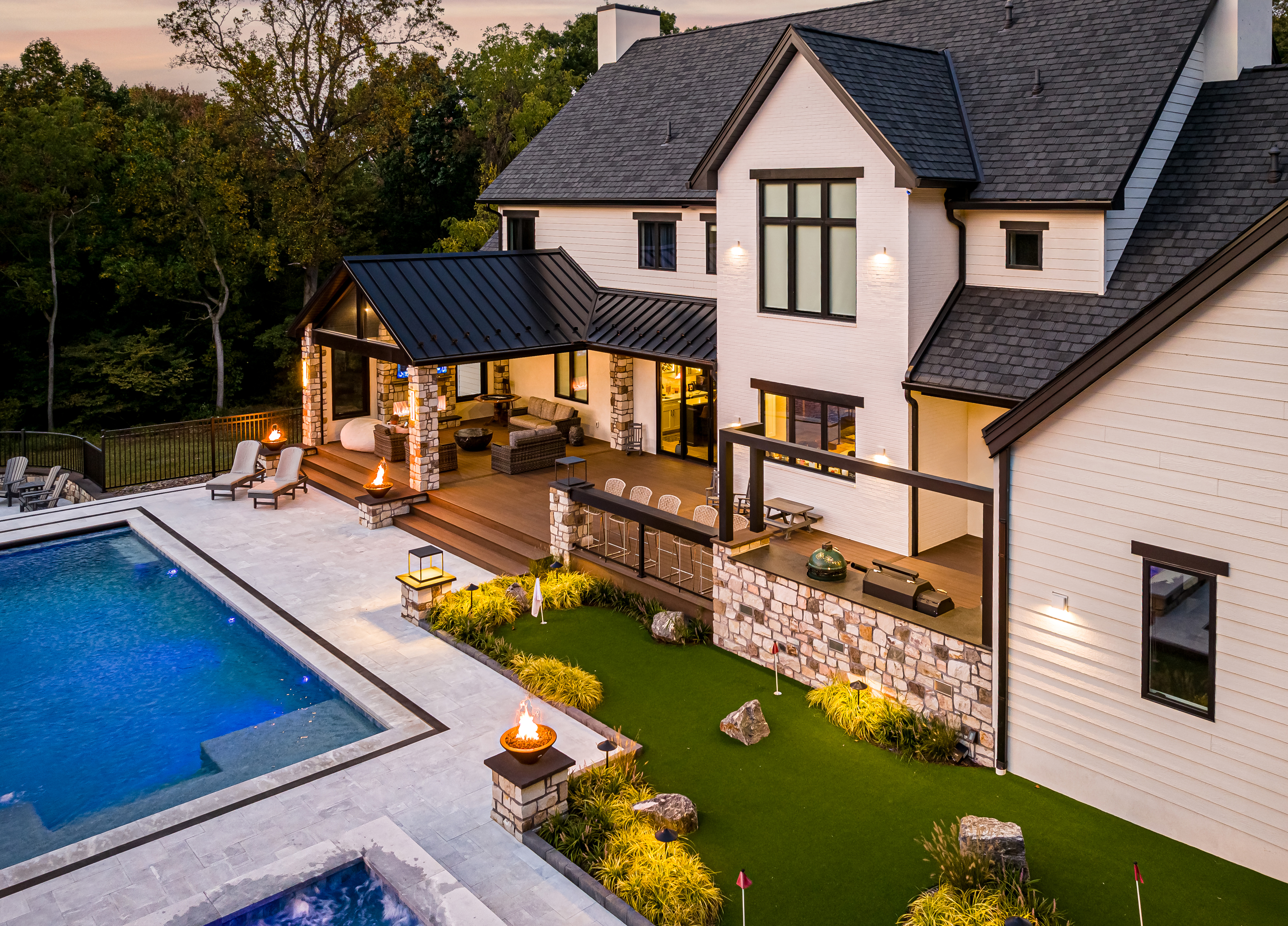 Elevated deck with round fire pit seating area and covered pavilion with outdoor kitchen