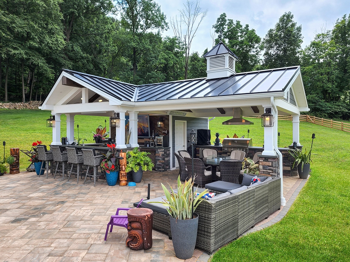 White covered outdoor kitchen with bar seating and grill