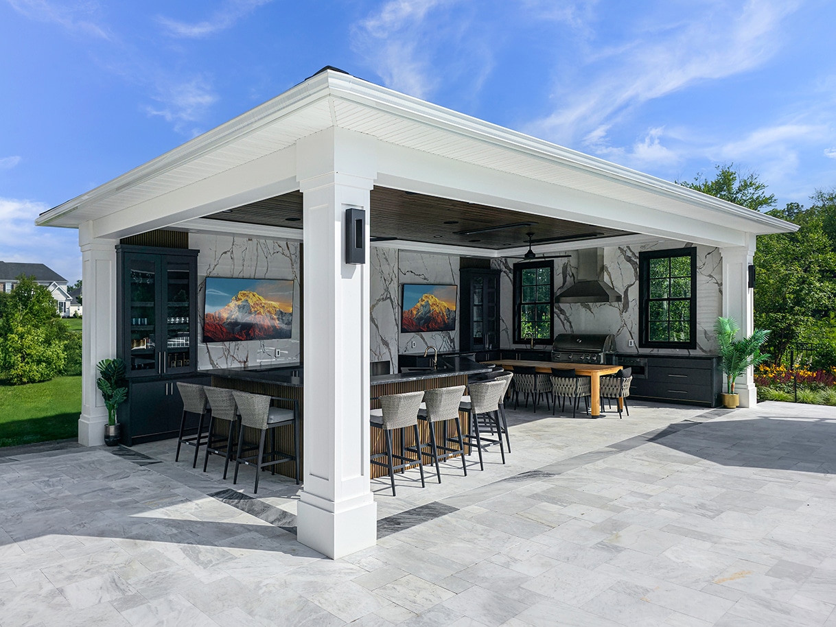 Stone pavilion with fireplace overlooking a pool and hot tub