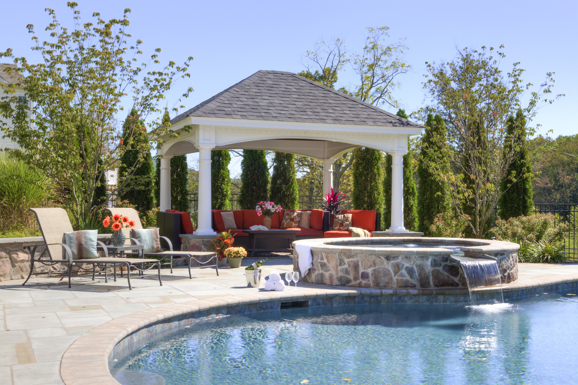 White vinyl pavilion with stone fireplace by a pool