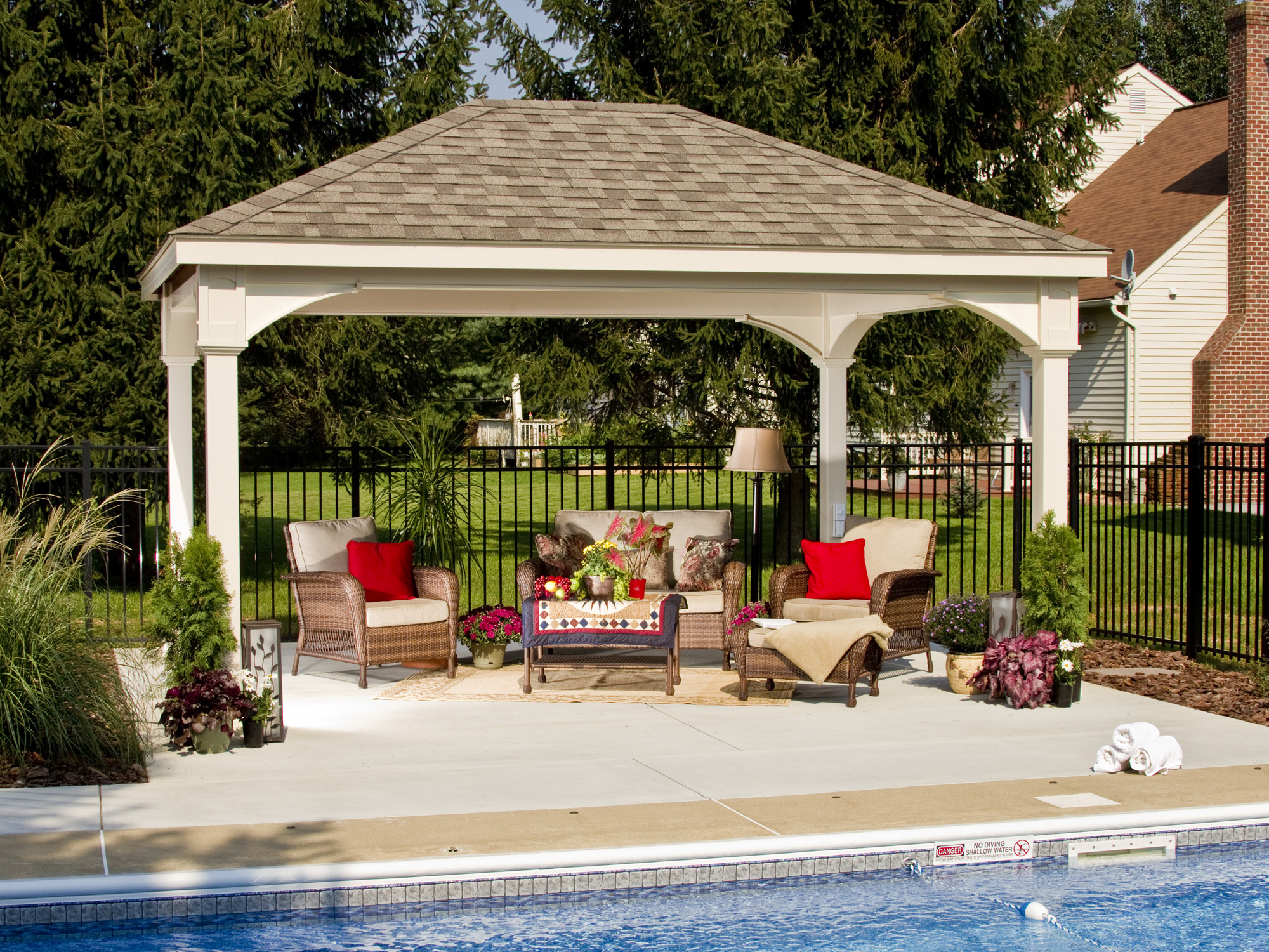 White vinyl hip-roof pavilion with arched columns at dusk beside a pool