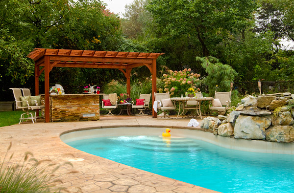 Wood artisan pergola with slatted roof over a dining table at dusk with string lights