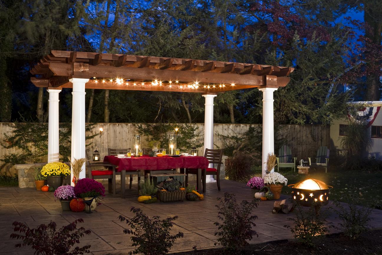 White vinyl pergola over a patio dining set beside a landscaped pond